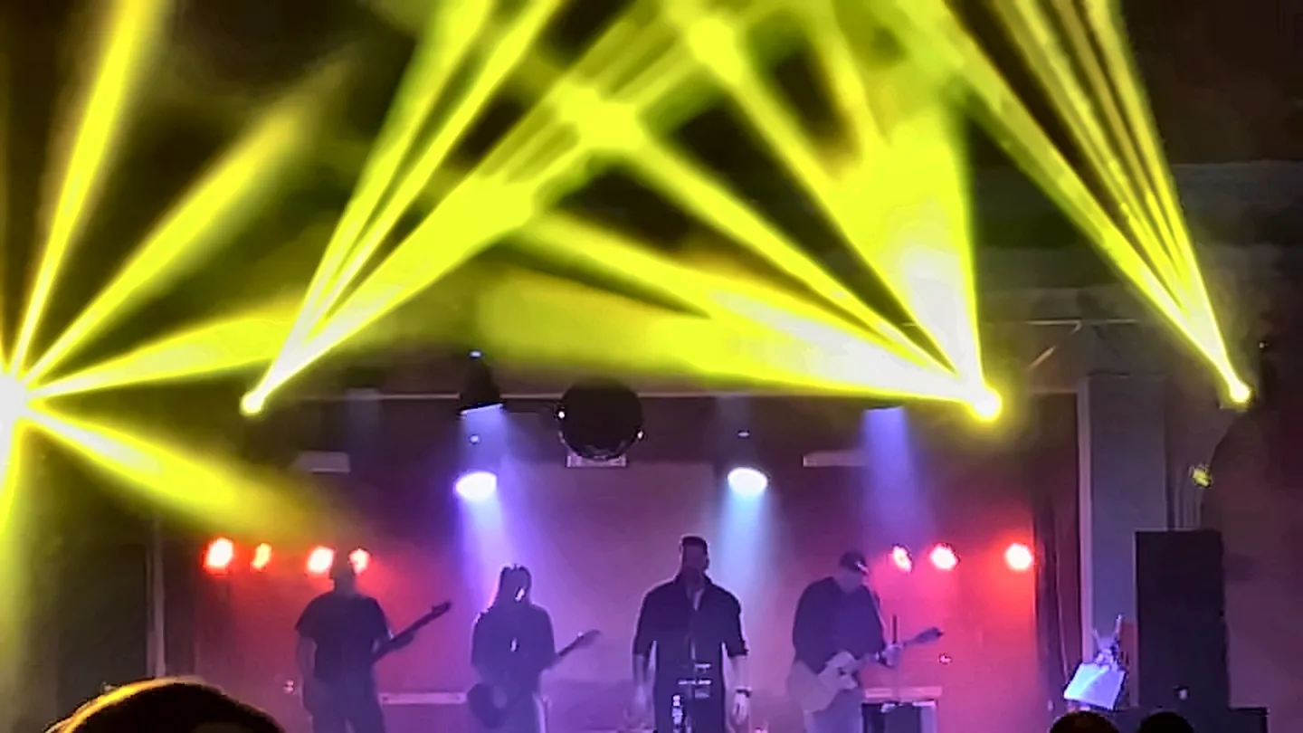 Koncert se scénickým osvětlením – žluté paprsky nad pódiem